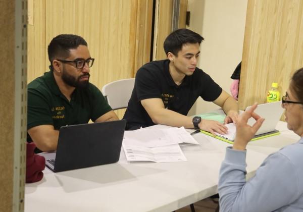 Two students help a community member with their tax return.